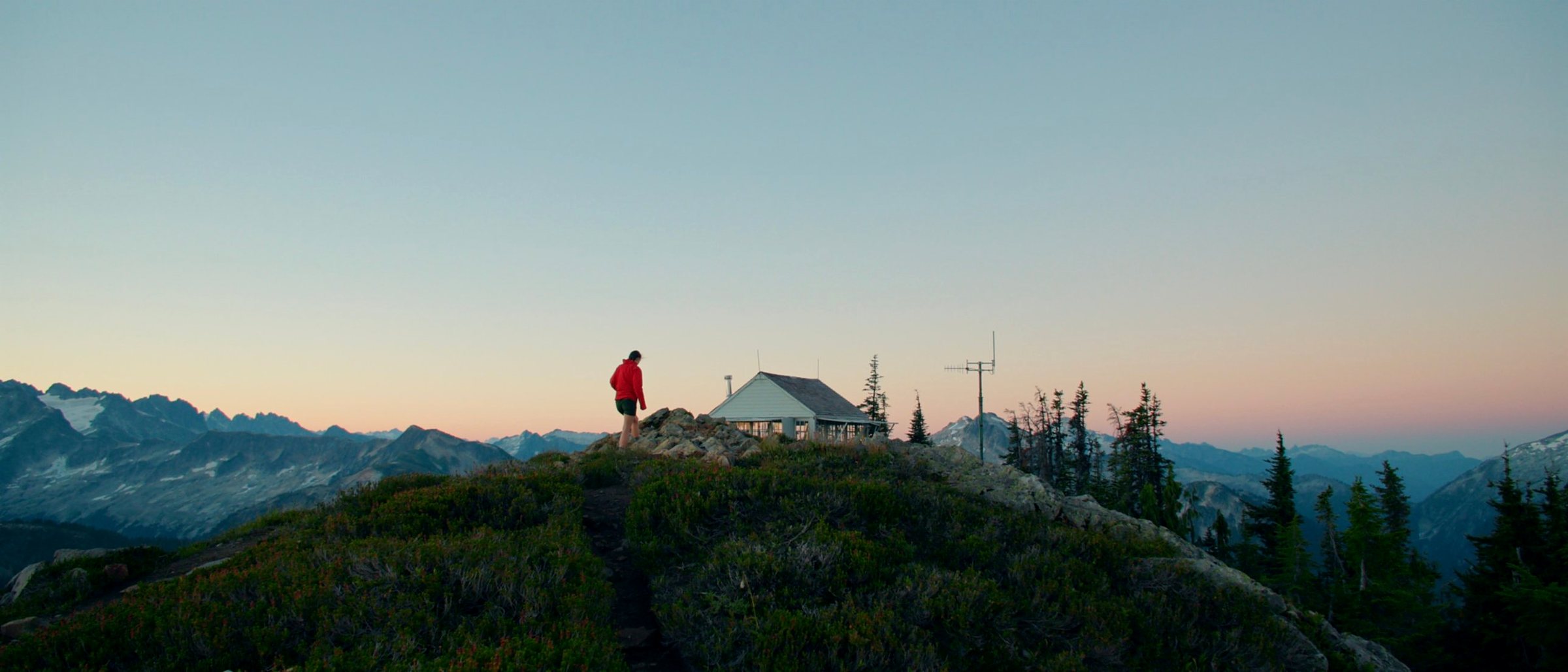 A hiker reaching a mountain lookout at dusk